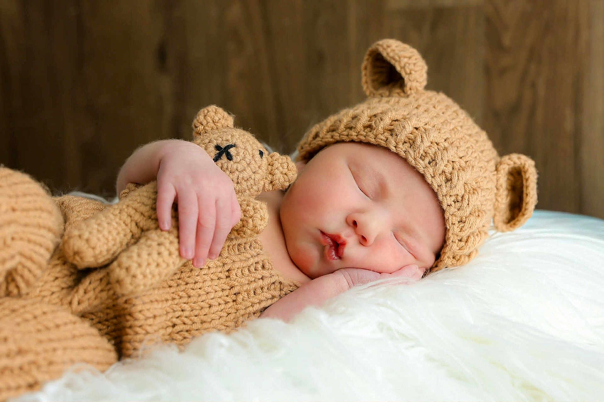Bentley joined the competition — help win amazing prizes! baby, sleeping, knitted_hat, knitted_outfit, teddy_bear, knitted_toy, cuddling, cozy, cute, infant, child, soft_texture, fluffy, white_blanket, wooden_background, portrait, peaceful, resting, closeup, indoors