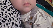 Mateo is registered to the contest to win money with this photo: baby, child, infant, portrait, face, wide_eyes, looking_at_camera, indoor, seated, overalls, shirt, clothing, leopard_print, cushion, blanket, bed, brown_hair, dark_hair, close_up, cozy