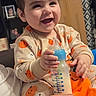 baby, child, toddler, smiling, laughing, portrait, indoor, home, pajamas, pumpkin_pattern, bottle, baby_bottle, drinking, seated, happy, face, hands, family_photos, curtain, furniture