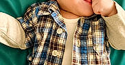 Mateo joined the competition — help win amazing prizes! baby, beige_shirt, buttoned_shirt, child, clothing, cute, expressive, face, hand_in_mouth, happy, infant, lying_down, plaid_shirt, portrait, short_hair, skin, smiling, teal_background, toddler, young_child