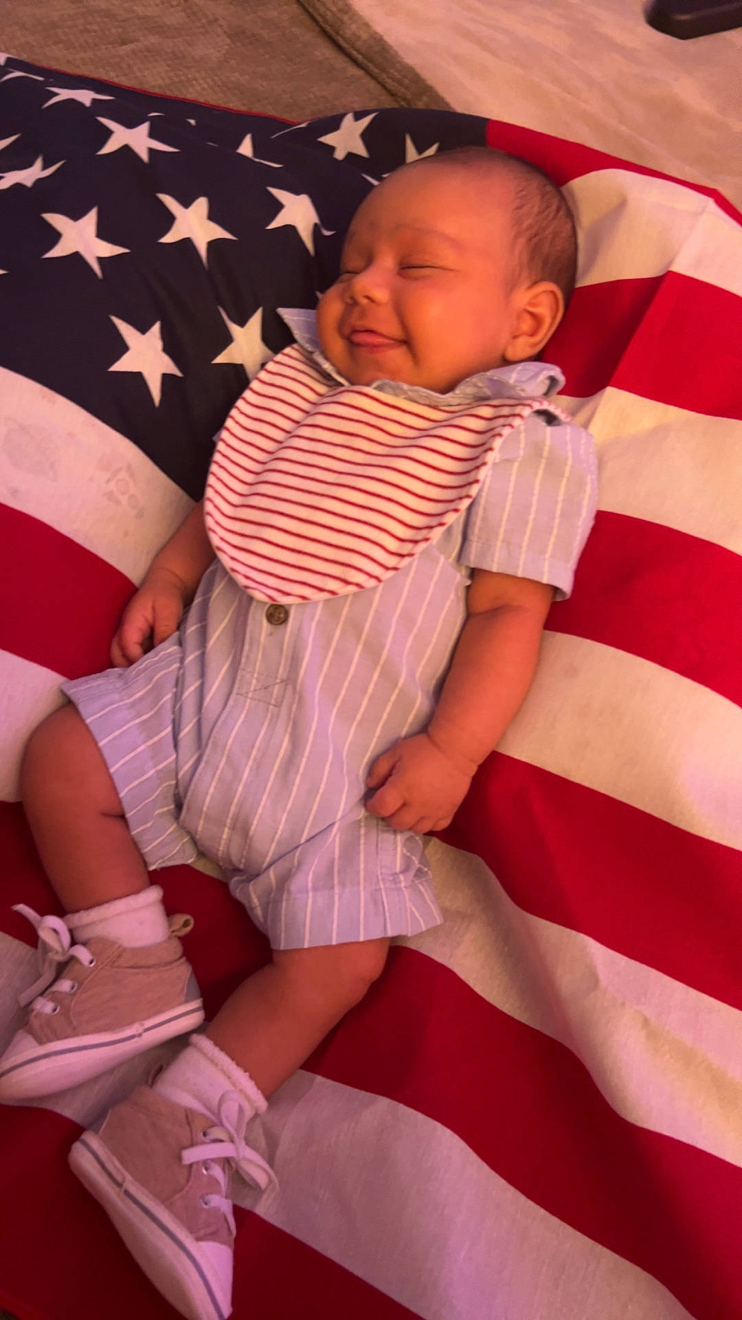 american_flag, baby, bib, child, cushion, cute, face, flag_pattern, footwear, hand, head, indoor, infant, portrait, relaxing, shoes, sleeping, smile, socks, striped_clothing