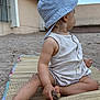 toddler, child, sand, hat, romper, sitting, outdoor, beach_mat, barefoot, hand, legs, wood, curious, summer, casual_clothing, side_view, sun_hat, nature, play, daylight