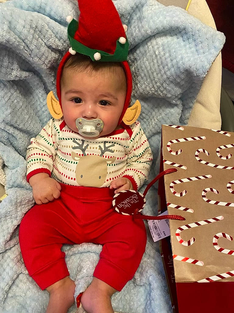 Jesus joined the competition — help win amazing prizes! baby, baby_toddler_clothing, cap, carmine, child, costume_hat, event, facial_expression, happy, hat, holiday, lap, people, person, red, sitting, sleeve, sun_hat, thigh, toddler