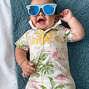 Jordan joined the competition — help win amazing prizes! baby, infant, sunglasses, blue, romper, flamingo, leaf_pattern, blanket, texture, happy, smiling, lying_down, cute, child, accessory, tropical, summer, fashion, indoors, portrait