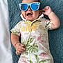 baby, infant, sunglasses, blue, romper, flamingo, leaf_pattern, blanket, texture, happy, smiling, lying_down, cute, child, accessory, tropical, summer, fashion, indoors, portrait