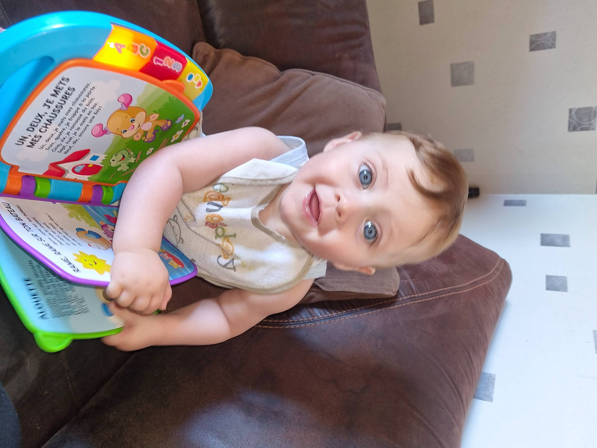 Gianny a rejoint le concours — aidez-le/la à gagner de superbes lots ! baby, baby_products, baby_toddler_clothing, baby_toys, cheek, child, flooring, fun, happy, hardwood, person, plastic, play, room, sitting, skin, smile, surprise, toddler, wood