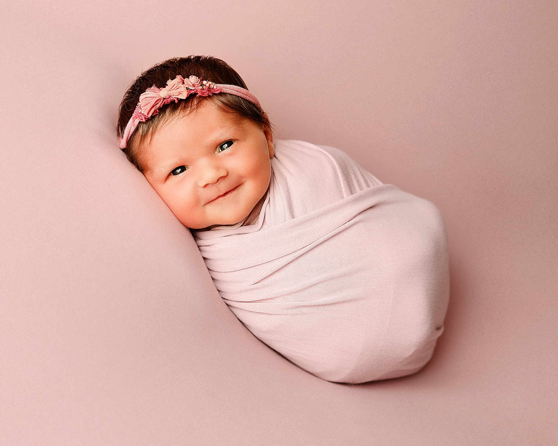 Amara joined the competition — help win amazing prizes! baby, newborn, wrapped, pink, headband, smiling, face, child, portrait, soft, cute, infant, studio, background, resting, peaceful, closeup, skin, expression, adorable
