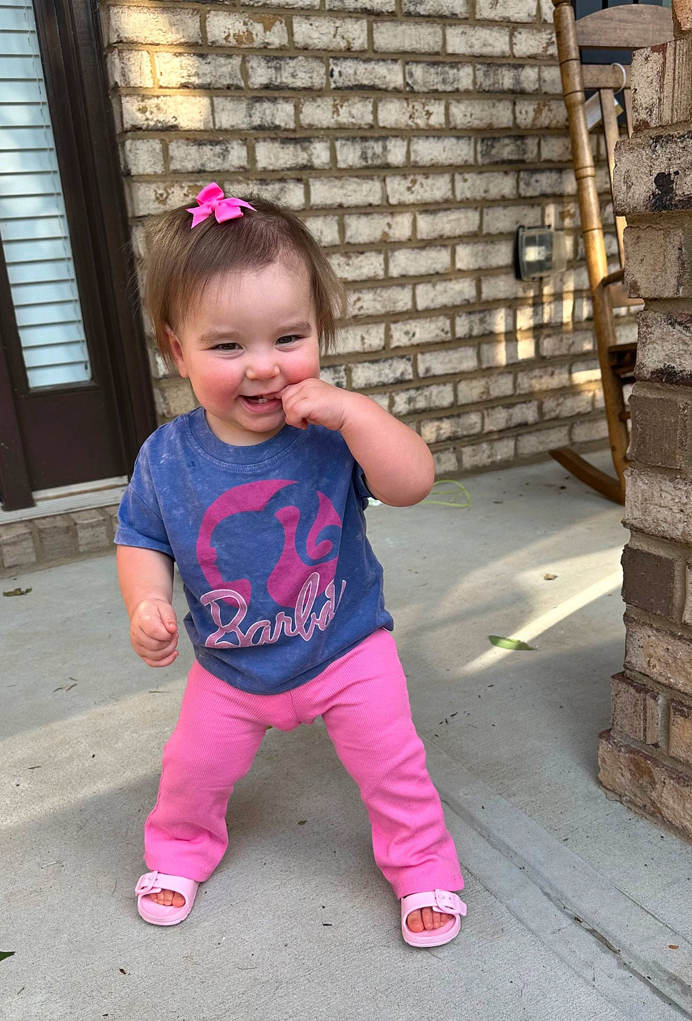 Sydney is registered to the contest to win money with this photo: baby, baby_toddler_clothing, brick, brickwork, cheek, chin, eye, face, facial_expression, fun, grass, happy, joy, magenta, person, pink, skin, sleeve, smile, standing