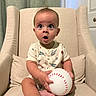armchair, baby, baseball, beige, child, curtain, cute, expression, feet, furniture, hands, indoor, infant, onesie, person, pillow, portrait, sitting, sports_theme, surprised