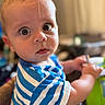 Theo is registered to the contest to win money with this photo: baby, blue_striped_shirt, bright, casual_clothing, child, close_up, curious, expression, eyes, face, hand, holding_object, human, indoor, infant, person, portrait, short_hair, skin, young_child