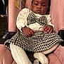 baby, infant, child, car_seat, pink, houndstooth, headband, white_tights, clothing, fashion, portrait, indoor, cute, person, seat, baby_clothes, hand, footwear, expression, young_child