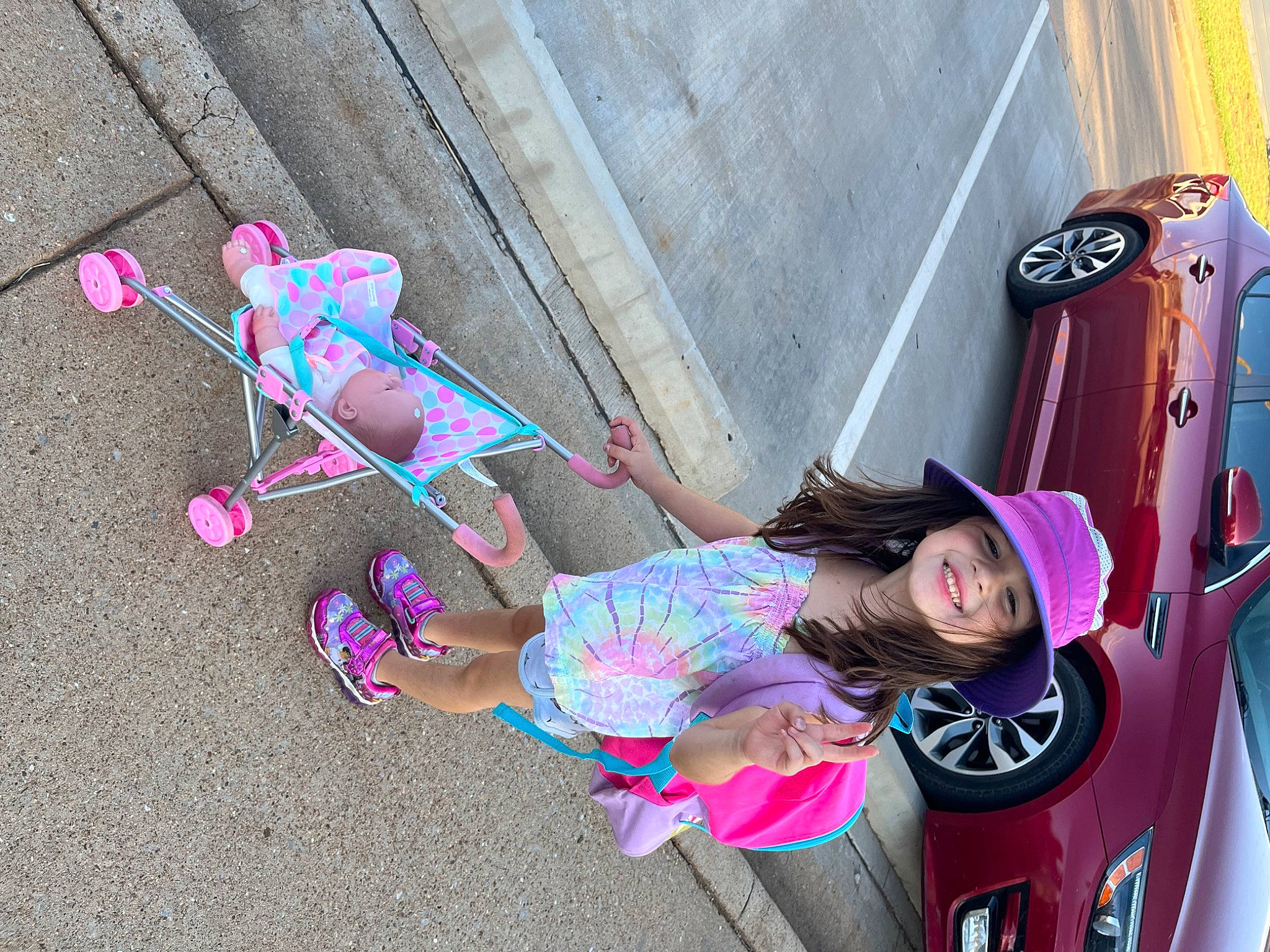 Jazmyn is registered to the contest to win money with this photo: automotive_exterior, automotive_lighting, automotive_tire, bumper, city, eyewear, fun, hat, headwear, joy, leisure, magenta, person, pink, product, recreation, sidewalk, sunglasses, tire, toddler