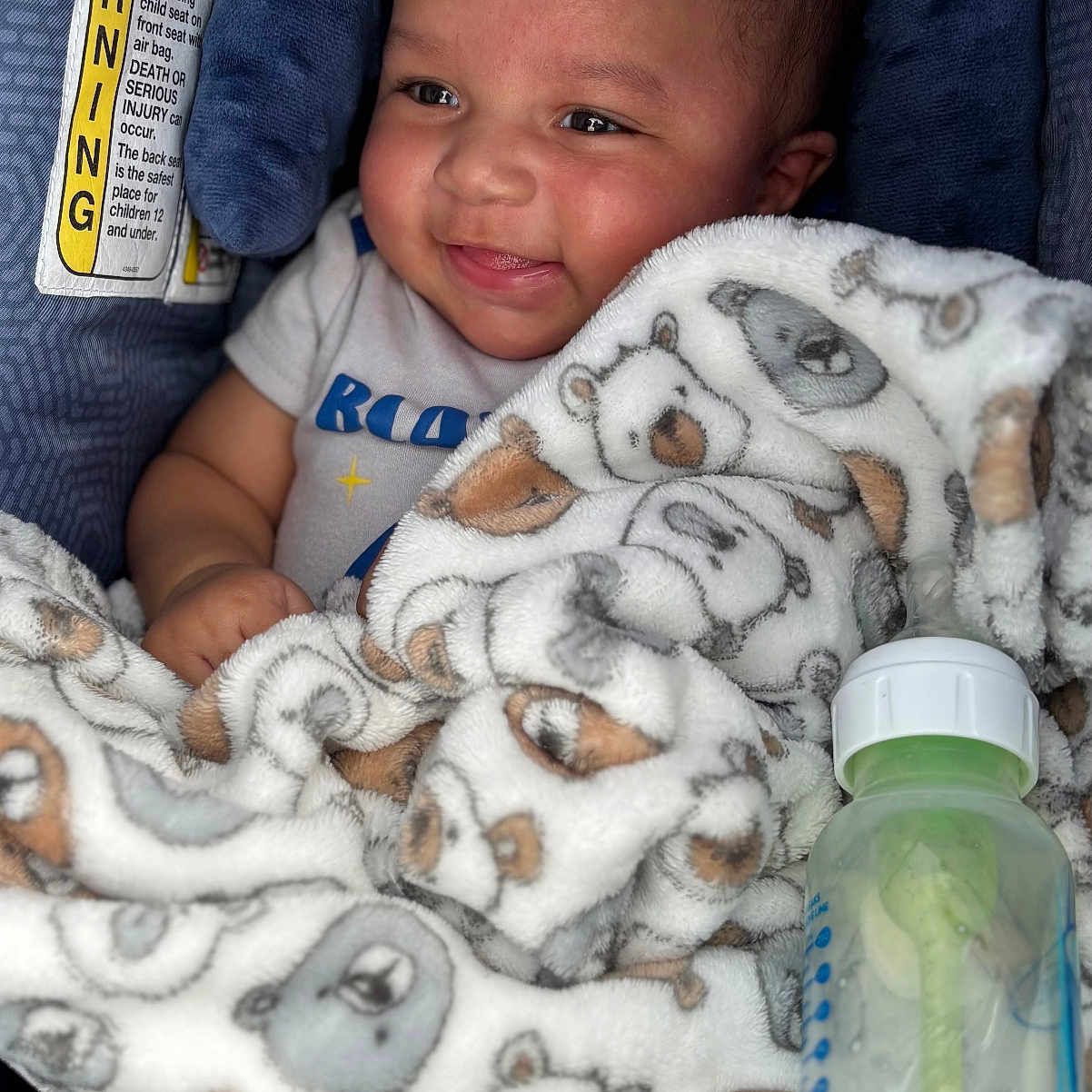 Ziyler is registered to the contest to win money with this photo: baby, bear_pattern, blanket, bottle, car_seat, child, clothing, cute, face, feeding_bottle, happy, infant, inside, joyful, lying_down, person, plush, smile, soft, toddler