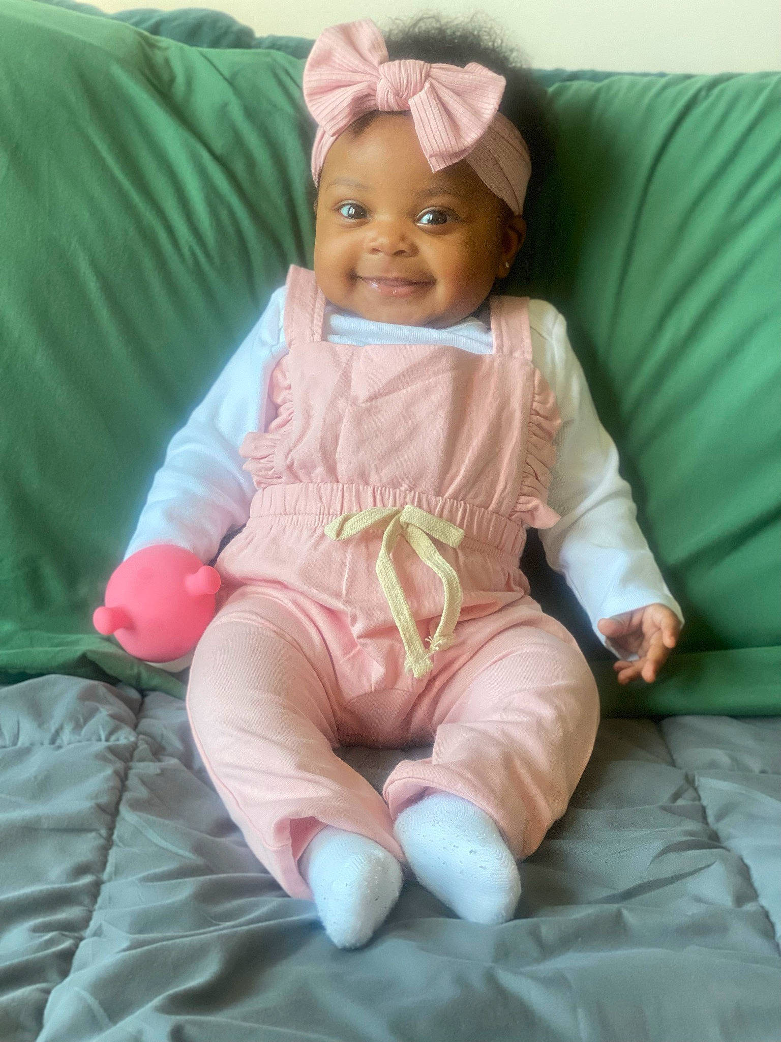 Ava-marie is registered to the contest to win money with this photo: baby, baby_toddler_clothing, barefoot, child, comfort, face, facial_expression, foot, fun, happy, human_leg, joy, knee, linens, magenta, person, pink, skin, sleeve, smile