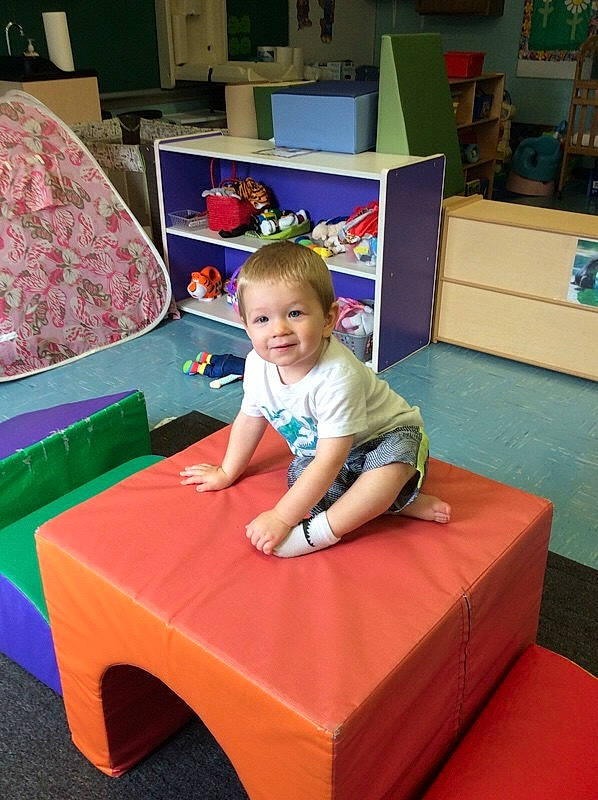 Greyson is registered to the contest to win money with this photo: baby, chair, child, comfort, couch, flooring, fun, joy, leisure, living_room, person, play, recreation, red, room, shorts, sitting, smile, studio_couch, t_shirt