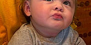 Nicolai joined the competition — help win amazing prizes! baby, child, curly_hair, gray_shirt, hands_clasped, thoughtful_expression, indoor, close_up, cute, chubby_cheeks, person, portrait, seated, looking_up, skin, infant, young_child, expression, casual_clothing, warm_background