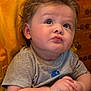 baby, child, curly_hair, gray_shirt, hands_clasped, thoughtful_expression, indoor, close_up, cute, chubby_cheeks, person, portrait, seated, looking_up, skin, infant, young_child, expression, casual_clothing, warm_background