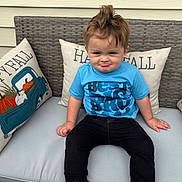 Nicolai is registered to the contest to win money with this photo: toddler, child, boy, blue_shirt, black_pants, sitting, outdoor_furniture, cushion, pillow, happy_fall, pumpkin, fall_decor, funny_face, hair_tuft, portrait, cute, smirk, casual_clothing, bench, daylight