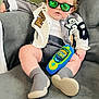 baby, child, sunglasses, jacket, toy, phone, couch, gray, sitting, cute, fashion, indoor, reflection, footwear, socks, person, portrait, casual, relaxed, young