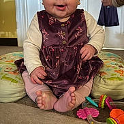 Skylar joined the competition — help win amazing prizes! baby, child, smiling, curly_hair, purple_dress, pink_tights, cushions, toys, carpet, indoor, door, long_sleeve_shirt, happy, sitting, floor, person, infant, playtime, cute, home