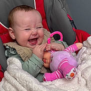 Charlotte is registered to the contest to win money with this photo: baby, infant, smiling, laughing, doll, plush_toy, car_seat, blanket, hand, clothing, cute, pink, red, gray, toy, happy, face, portrait, cozy, child