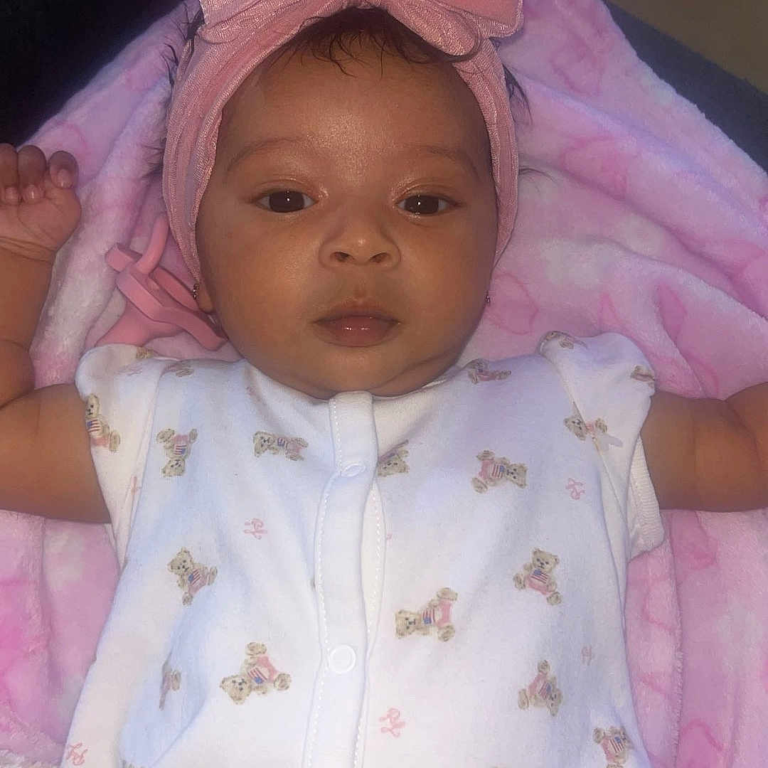 Kaylani joined the competition — help win amazing prizes! baby, infant, child, pink_bow, blanket, onesie, teddy_bear_print, headband, portrait, cute, lying_down, soft_texture, indoors, young_child, sleepwear, adorable, face, small_hands, baby_girl, clothing