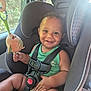 child, toddler, car_seat, smile, toy, plush_toy, car_interior, seatbelt, window, sunlight, greenery, happy, sitting, infant, clothing, safety, baby, cute, indoors, portrait