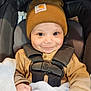 baby, child, smiling, hat, car_seat, blanket, sweater, indoors, cute, infant, face, person, clothing, warm, bundle, seatbelt, portrait, happy, hands, cozy