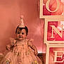 Delilah is registered to the contest to win money with this photo: baby, child, birthday, party_hat, pink_dress, flowers, balloons, blocks, floor, wall, celebration, one_year_old, smile, sitting, cute, indoors, decorations, festive, happy, portrait