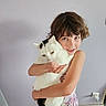 Lucie participe au concours pour gagner de l'argent avec cette photo : child, cat, pet, hugging, smiling, portrait, indoors, home, white_cat, black_and_white, animal, girl, curly_hair, dress, floor, wall, power_outlet, cuddling, companion, photography