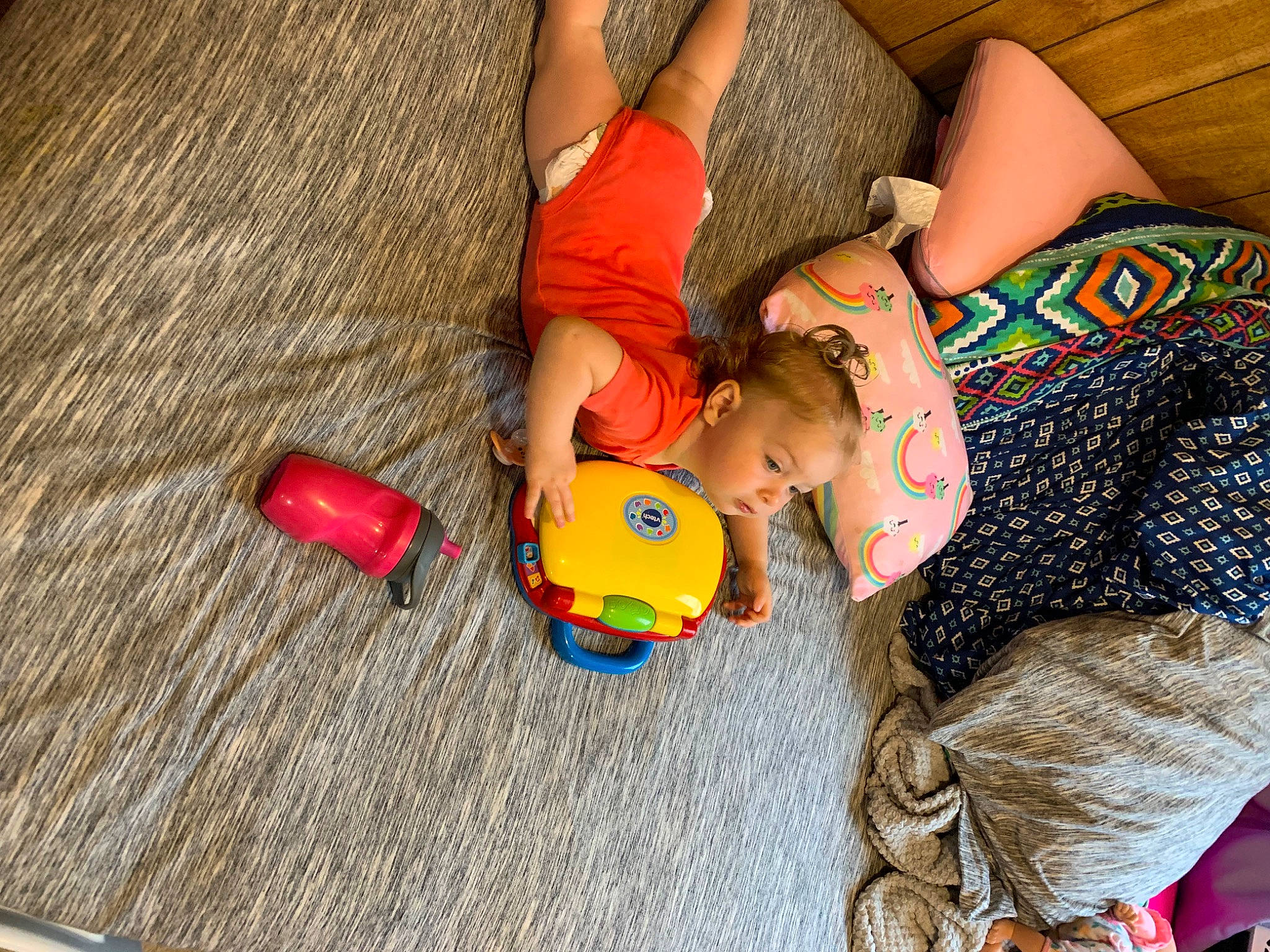 Kadence is registered to the contest to win money with this photo: abdomen, baby_toys, child, comfort, flooring, fun, happy, hardwood, human_leg, leisure, pattern, person, room, sand, sitting, thigh, toddler, toy, toy_vehicle, vacation
