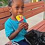 Kasen joined the competition — help win amazing prizes! child, boy, popsicle, bench, outdoor, blue_shirt, shorts, black_plastic_bag, urban, daytime, smiling, food, snack, summer, tree, sidewalk, building, street, person, casual