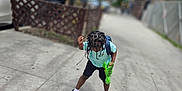 Kasen joined the competition — help win amazing prizes! child, toy, green_toy, sidewalk, urban, braided_hair, backpack, shorts, tshirt, crocs, tree, car, concrete, street, fence, building, daylight, outdoor, person, playful
