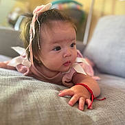 Maite is registered to the contest to win money with this photo: baby, infant, child, cute, ribbon, bracelet, hand, face, couch, furniture, indoors, portrait, pink, clothing, skin, expression, curious, young, cozy, soft