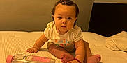 Maite joined the competition — help win amazing prizes! baby, infant, child, sitting, mattress, bottle, comb, hair_tie, curious, indoors, bedroom, wall, pajamas, cute, face, person, skin, hand, foot, expression