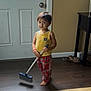 Gael joined the competition — help win amazing prizes! child, broom, pajamas, yellow_tank_top, barefoot, wooden_floor, door, indoor, shoes, carpet, floor, standing, person, home, cleaning, plaid_pants, young_child, room, furniture, curious