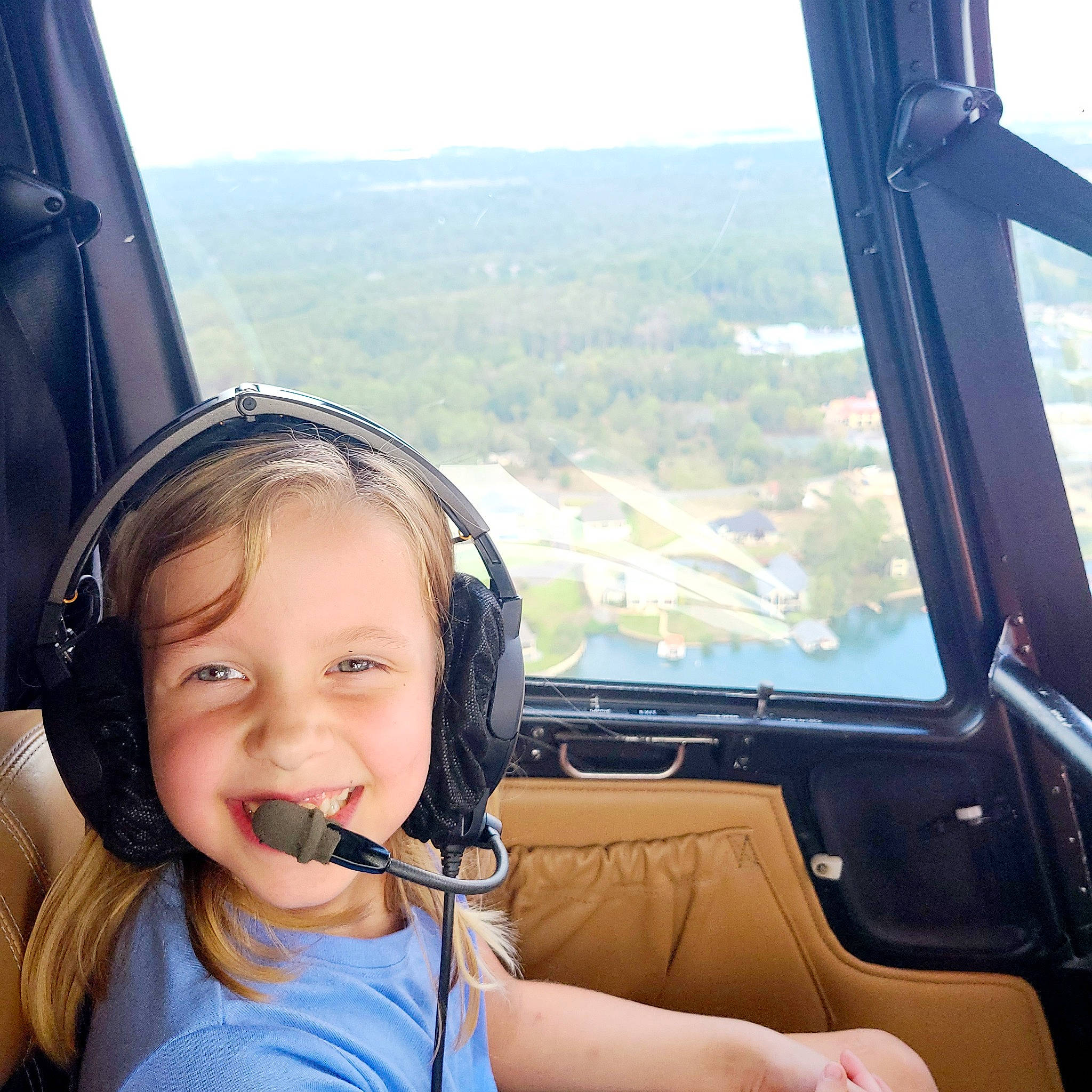 Leah is registered to the contest to win money with this photo: aerospace_manufacturer, air_travel, aircraft, audio_equipment, aviation, cockpit, electronic_device, gadget, happy, hearing, helicopter_pilot, joy, leisure, person, pilot, sky, smile, steering_wheel, technology, toddler