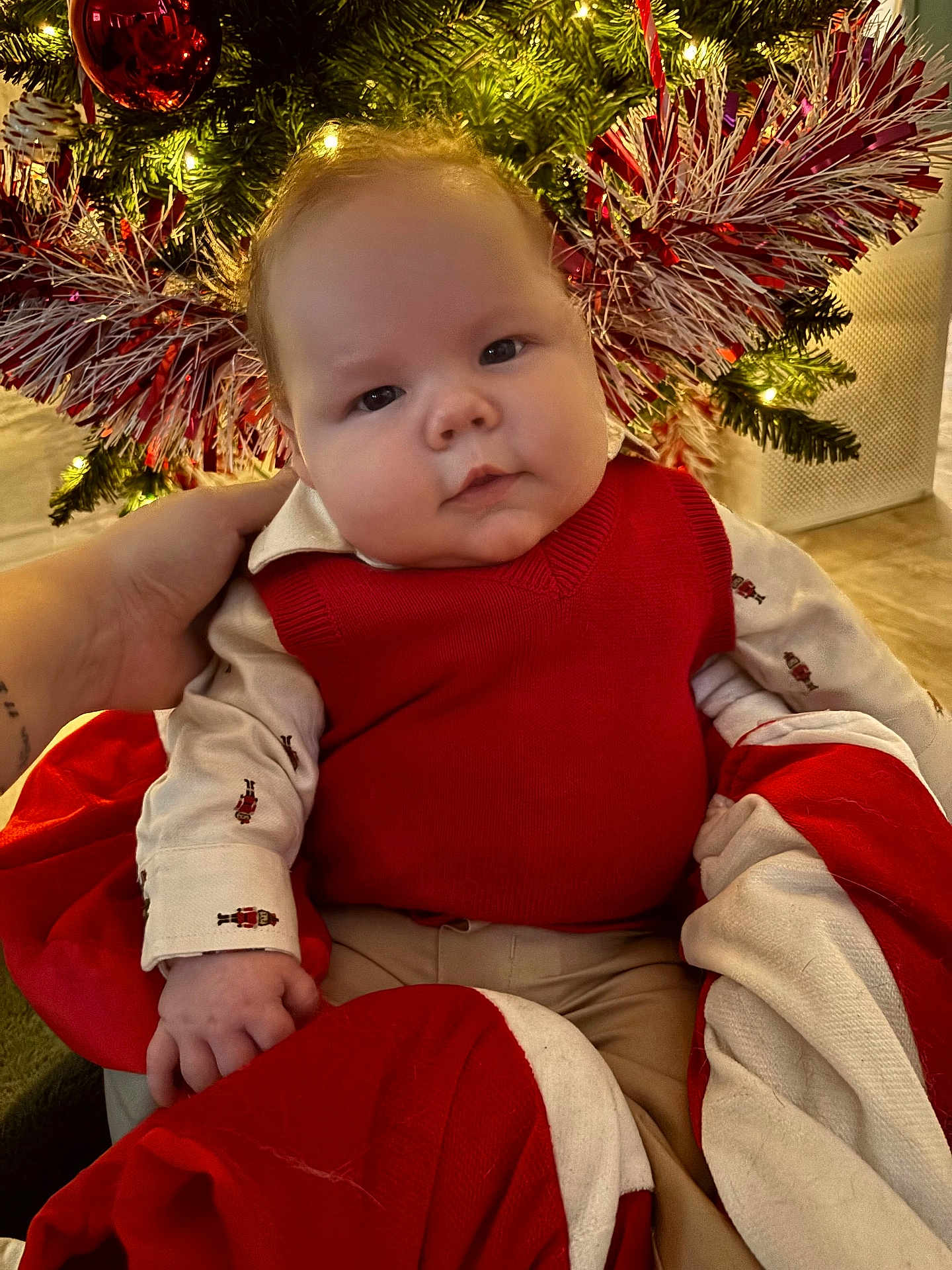 Ace joined the competition — help win amazing prizes! baby, infant, child, christmas_tree, holiday, festive, red_clothing, blanket, ornament, decorations, hand, indoors, cute, face, smile, warm_lighting, seasonal, toddler, portrait, cozy