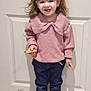 toddler, child, girl, pigtails, smiling, indoor, cookie, pink_sweater, dark_pants, socks, animal_socks, standing, floor, door, hair, happy, clothing, person, portrait, casual