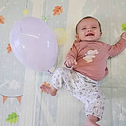 Valentine participe au concours pour gagner de l'argent avec cette photo : baby, balloon, smiling, play_mat, infant, happy, child, lying_down, pink_clothing, patterned_pants, indoor, cute, one_person, young_child, foot, hand, face, head, toy, colorful_background