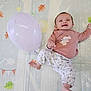 baby, balloon, smiling, play_mat, infant, happy, child, lying_down, pink_clothing, patterned_pants, indoor, cute, one_person, young_child, foot, hand, face, head, toy, colorful_background