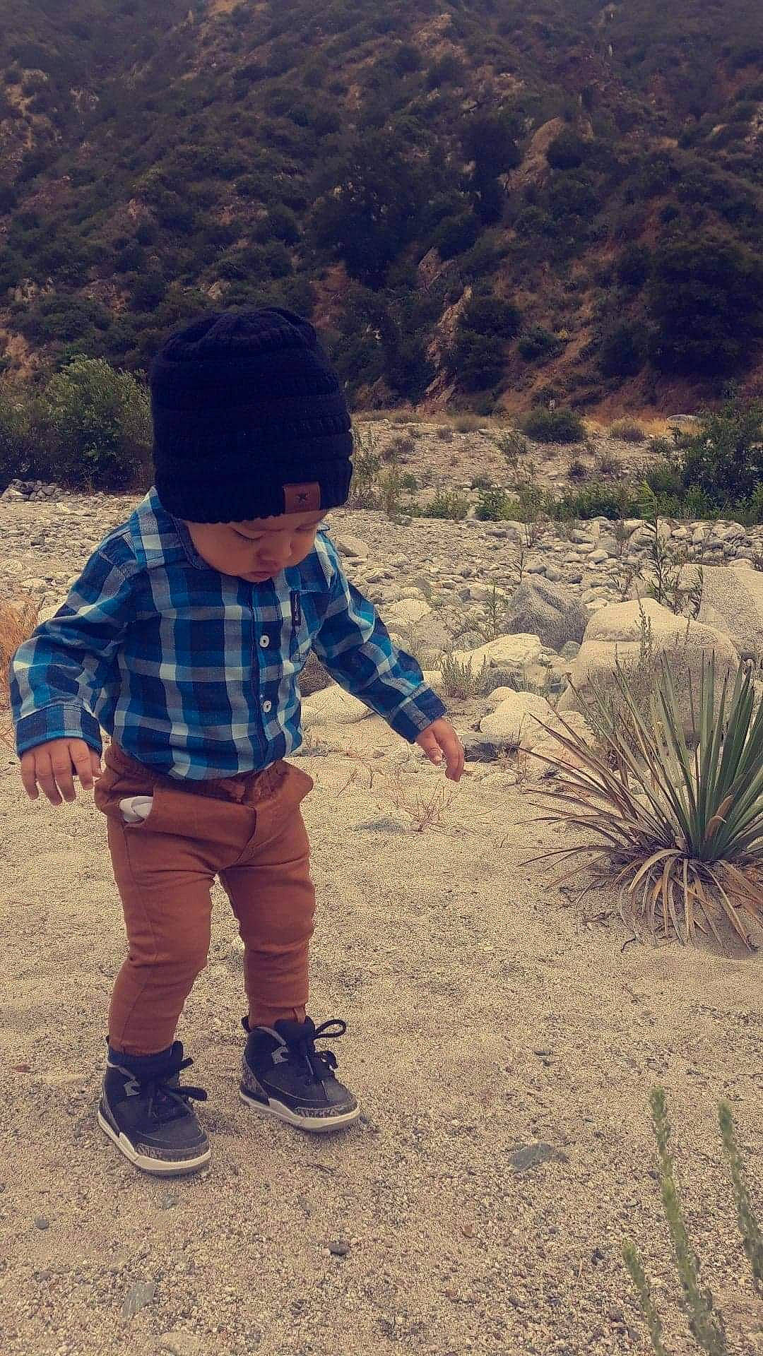 Melvyn is registered to the contest to win money with this photo: cap, child, headgear, landscape, mountain, perennial_plant, person, plant, sand, smile, toddler, tourism, vacation, walking, wilderness