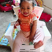 Amina is registered to the contest to win money with this photo: toddler, child, smiling, indoor, chair, toy, pink_bows, orange_shirt, light_pink_pants, happy, cute, hair_bows, carpet, playroom, plastic_chair, baby, person, young_child, sitting, holding_toy