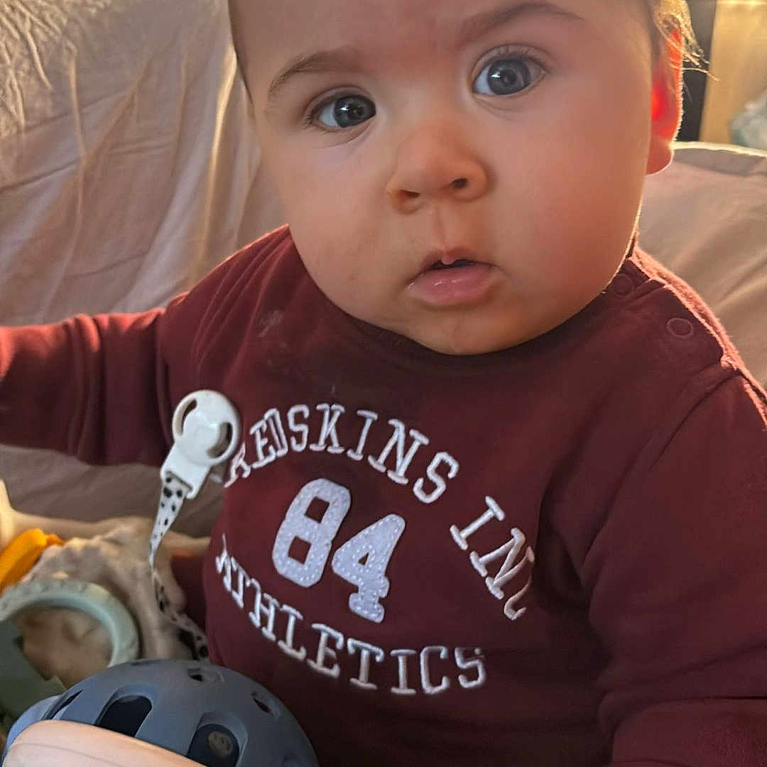 Kaïs a rejoint le concours — aidez-le/la à gagner de superbes lots ! baby, child, closeup, colorful_toys, curious, cute, expression, face, hand, indoor, infant, light, maroon_clothing, pacifier_clip, person, playtime, sitting, soft_light, toy, young_child