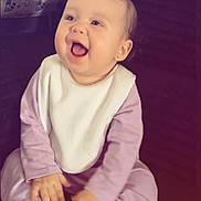 Khalani joined the competition — help win amazing prizes! baby, child, infant, smiling, laughing, portrait, sitting, pink_outfit, bib, bow, indoor, cozy, happy, face, hands, shoes, white_shoes, long_sleeves, baby_clothing, candid_photo