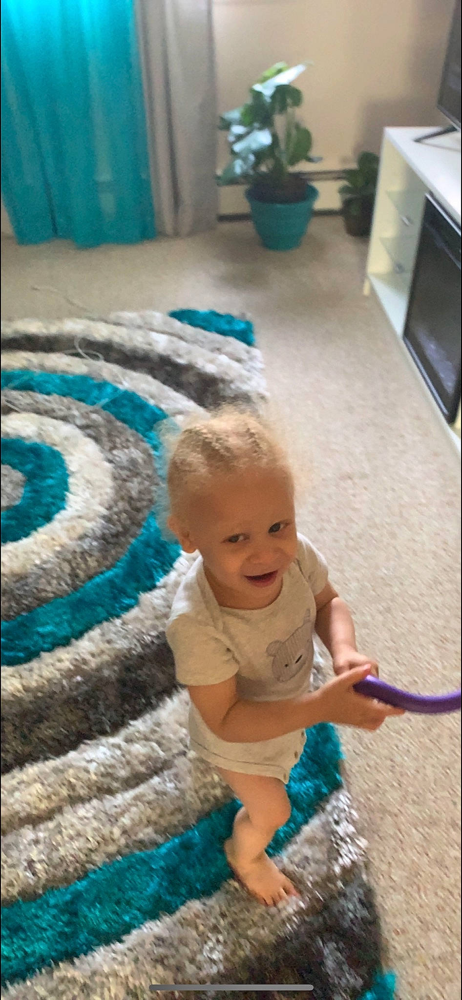 Lucci is registered to the contest to win money with this photo: baby, baby_toddler_clothing, blue, child, electric_blue, floor, flooring, flowerpot, fun, green, happy, houseplant, leisure, mammal, person, smile, standing, television, toddler, vertebrate
