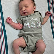 Mirabelle is registered to the contest to win money with this photo: arms_raised, baby, blanket, changing_pad, cute, hands, indoors, infant, legs, lying_down, mother, newborn, onesie, peaceful, photography, portrait, sleeping, socks, striped_background, text_on_clothing