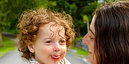 Louie joined the competition — help win amazing prizes! child, toddler, curly_hair, woman, adult, outdoor, nature, trees, greenery, road, holding, playful, tongue_out, white_clothing, lace, tattoo, smile, portrait, family, affection