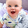 baby, infant, smiling, blue_eyes, dinosaur_print, onesie, blanket, pillow, soft_texture, happy, cute, child, portrait, indoors, closeup, young, playful, cheerful, crawling, bright