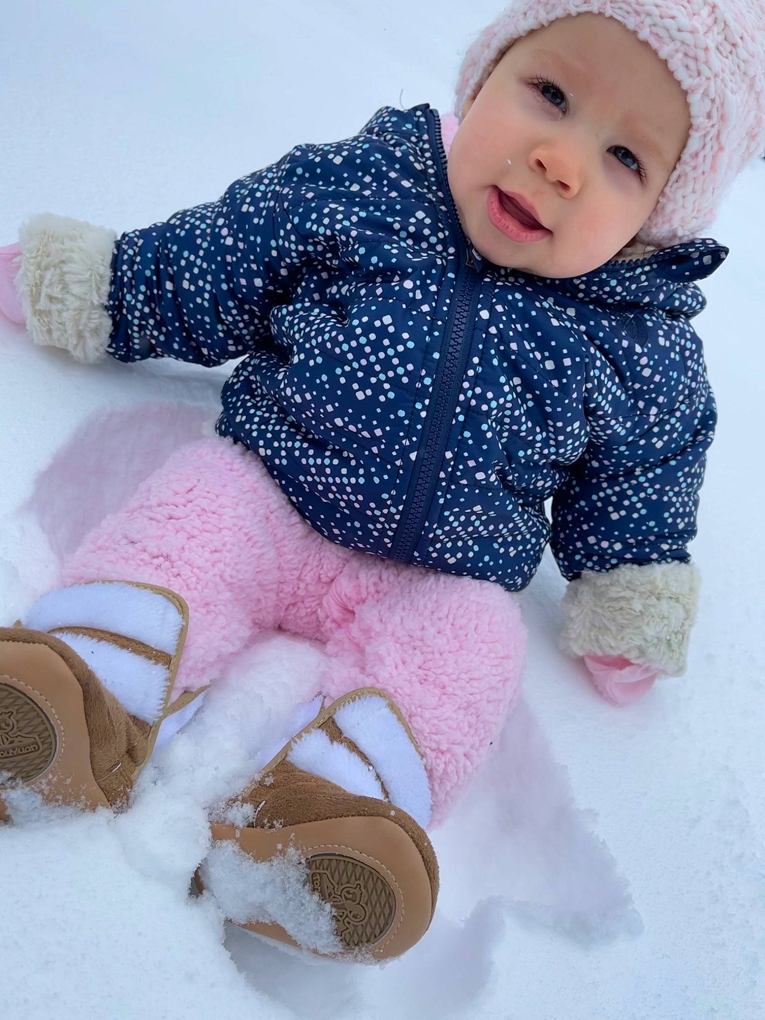 Marianna is registered to the contest to win money with this photo: baby_toddler_clothing, cheek, child, face, facial_expression, freezing, head, headgear, headwear, human_body, leg, organ, person, photograph, pink, skin, sleeve, smile, snow, textile